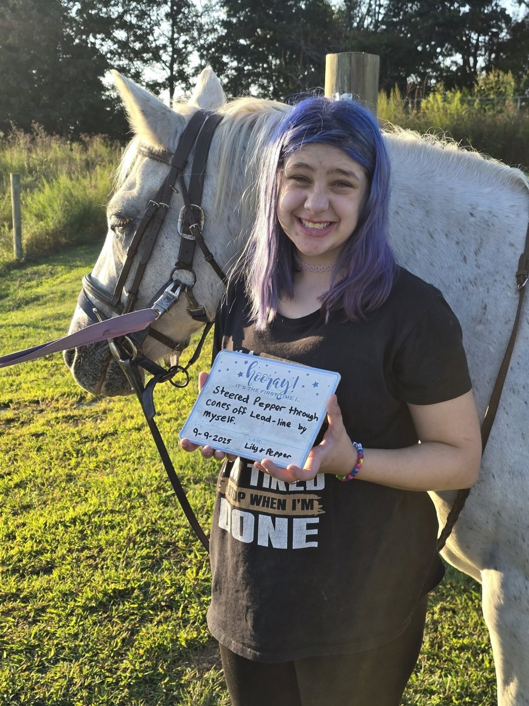 A young rider beside a horse holding a card celebrating riding with a bareback pad.